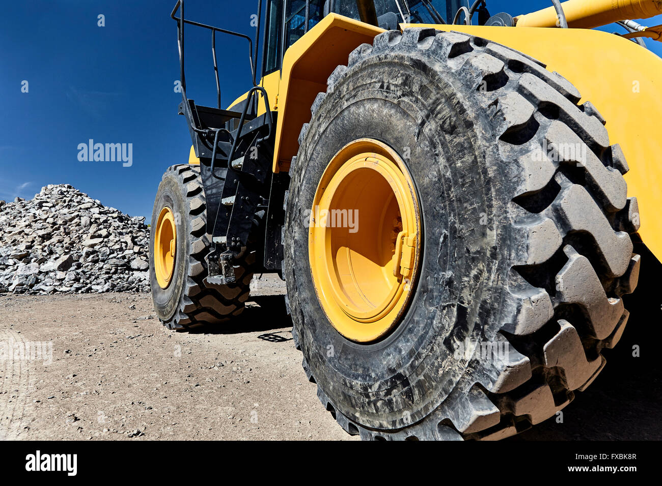 Bau-Baumaschinen-Lader und Eimer auf Baustelle mit Kies und Felsen Stockfoto