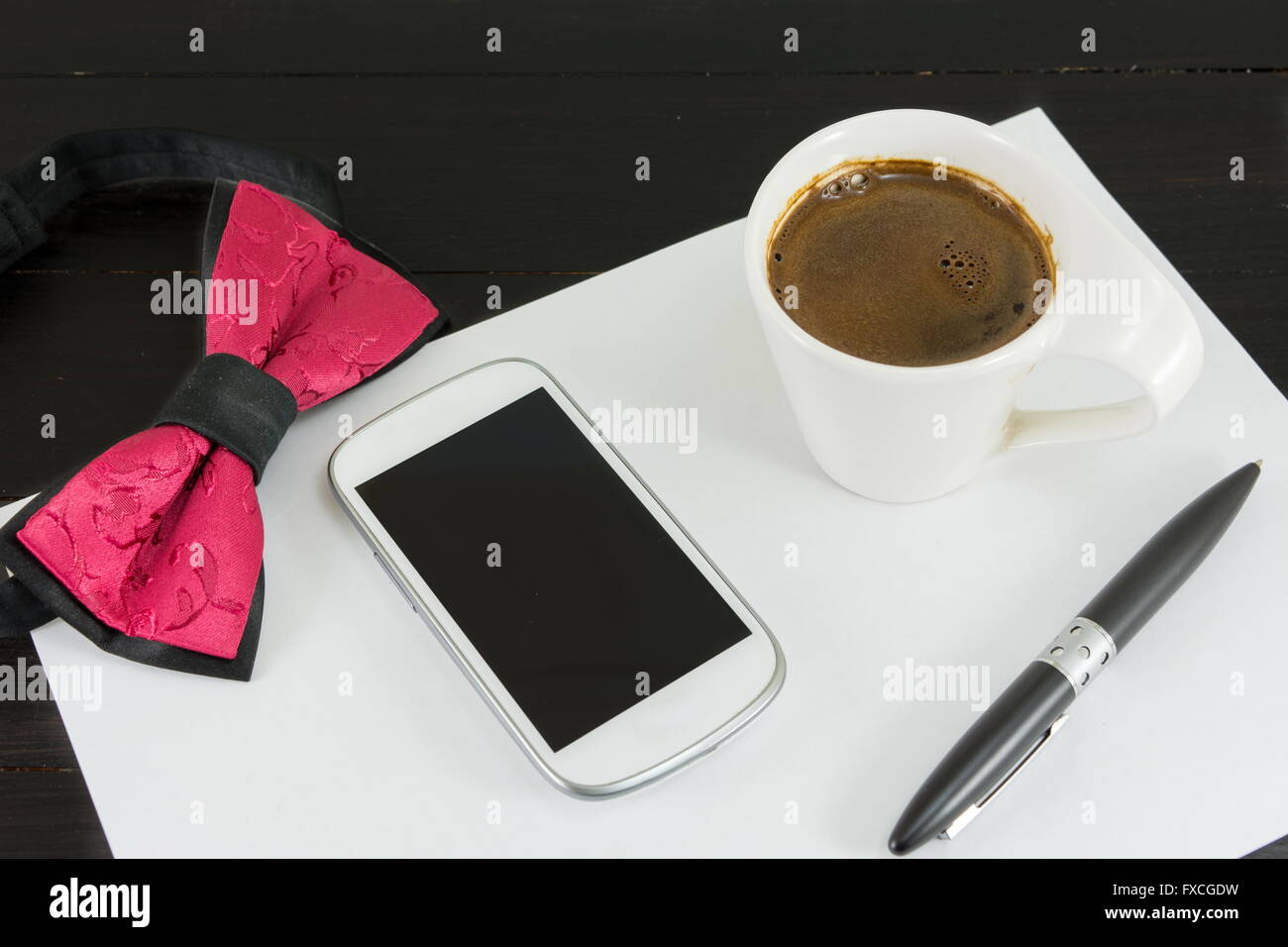 Tasse Kaffee für einen guten Arbeitstag. Kaffee und Tech Zubehör am schwarzen Tisch Stockfoto