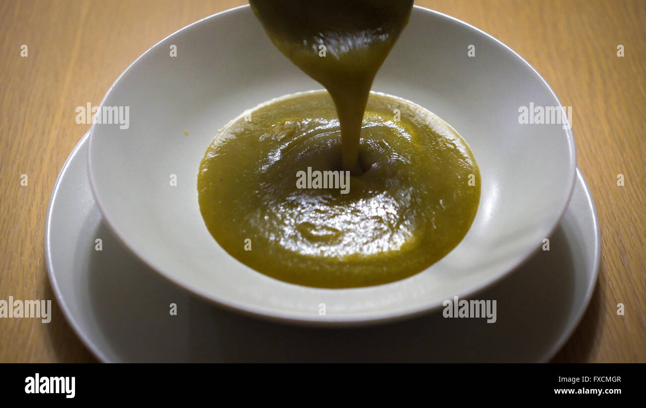 Gemüsesuppe wird in einer weißen Schale gegossen. Stockfoto