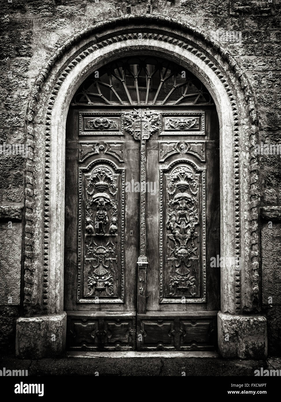 Altes Holztor mit Steingewölbe graviert mit dämonischen Figuren. Stockfoto