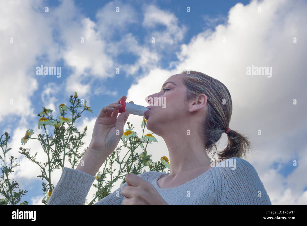Junge Frau mit Inhalator zur Behandlung von Asthma allergisch auf Blumen Wiese Stockfoto