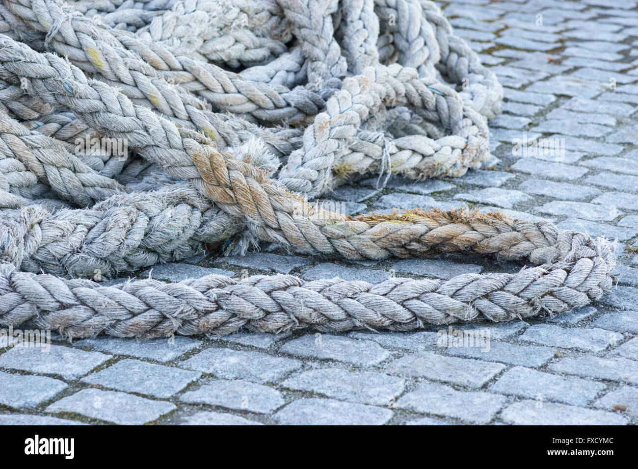 Dicke alte Marine Takelage Seil verheddert in den Knoten auf Kopfsteinpflaster Pier, selektiven Fokus Stockfoto