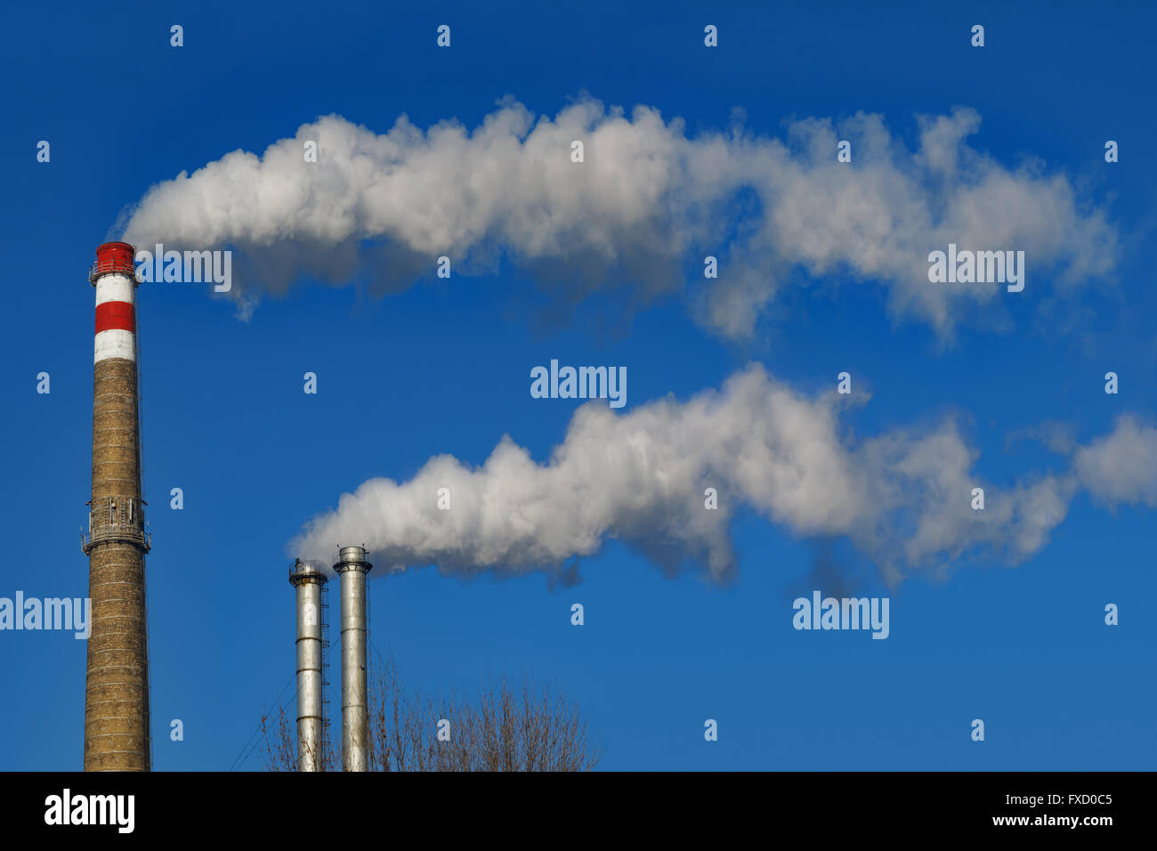 Schornsteine Rauchen.  Rohre emittiert lange Rauchfahne auf blauen Himmelshintergrund. Stockfoto