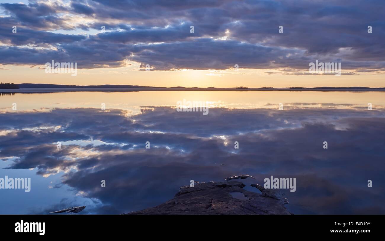 Dramatische Wolken und lebendigen Farben der Sonnenuntergang an einem See in Finnland eine ruhige Frühlingsabend. Die Sonne befindet sich direkt hinter den Wolken rea Stockfoto