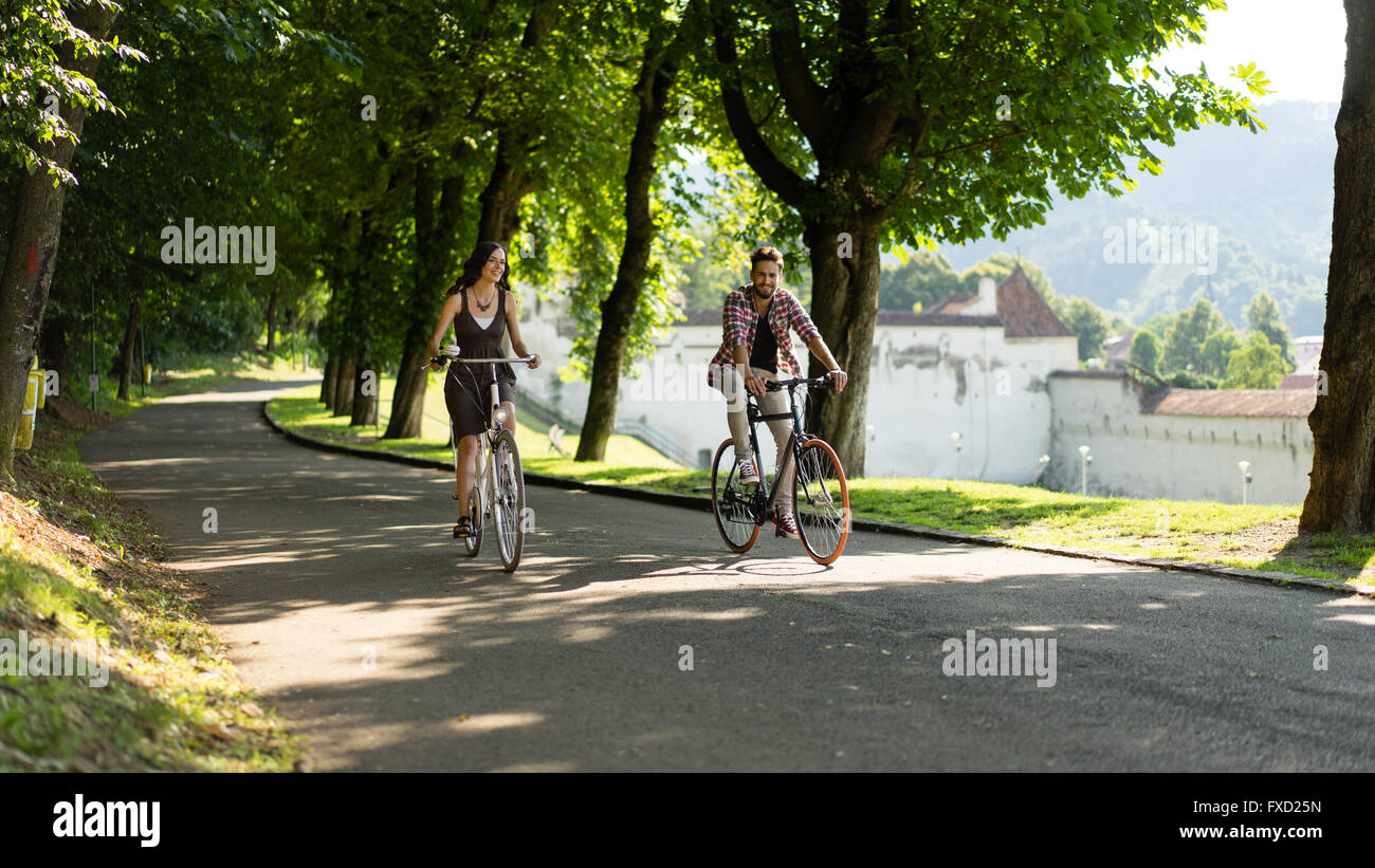 Freunde genießen das Fahrrad in einer Gasse mit Bäumen an einem Sommertag am Rande der mittelalterlichen Stadt Stockfoto