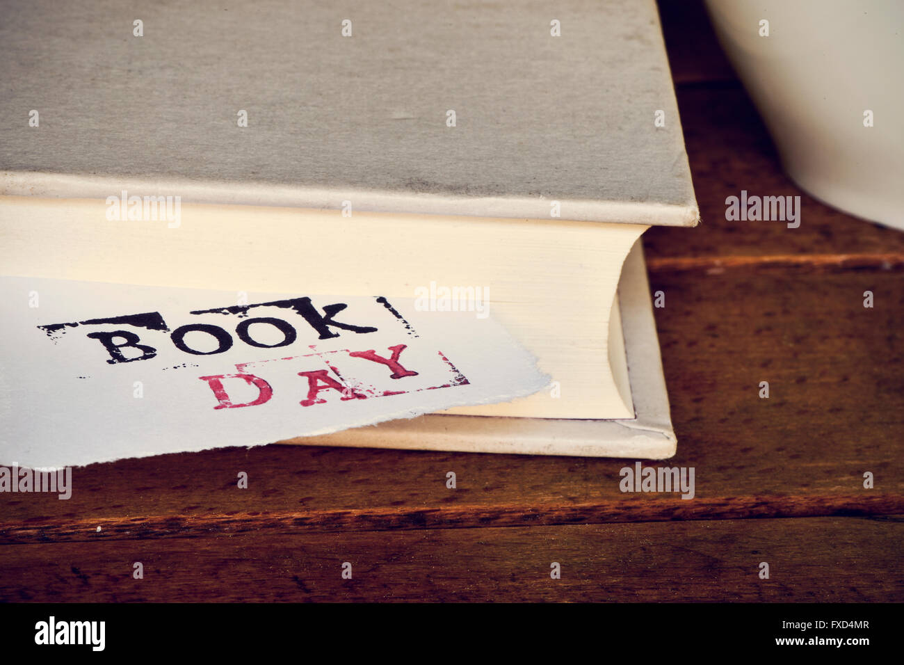 Nahaufnahme von einem Stück Papier Witz auftauchen aus einem Buch, Tag des Buches der Text platziert auf einem rustikalen Holztisch neben einer Tasse Cof Stockfoto