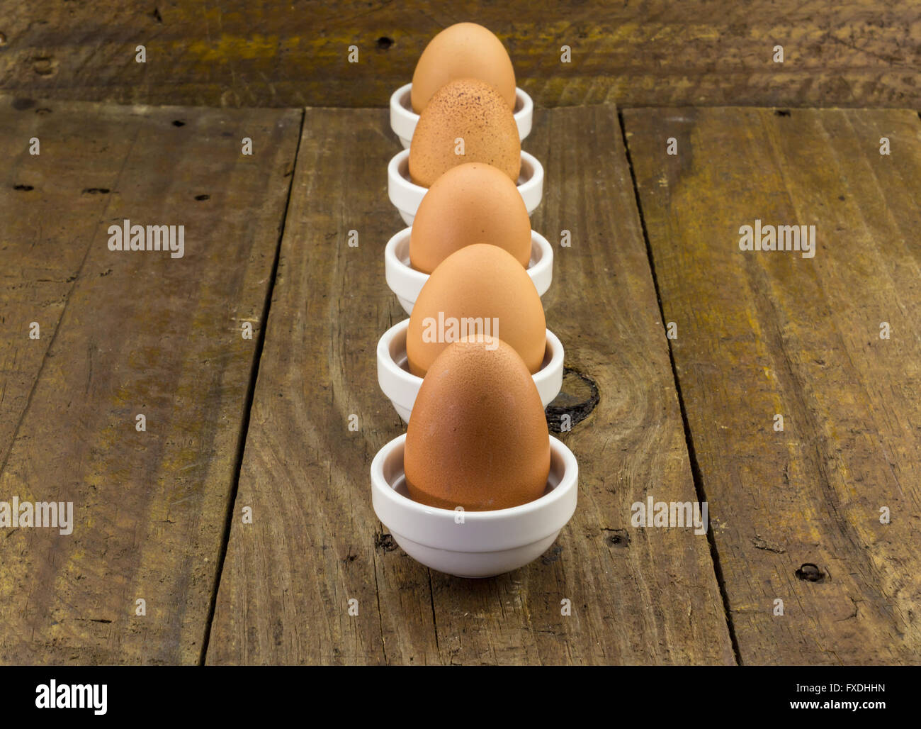 Fünf Hühnereier in Folge sinkende Perspektive auf rustikalen Holztisch Stockfoto