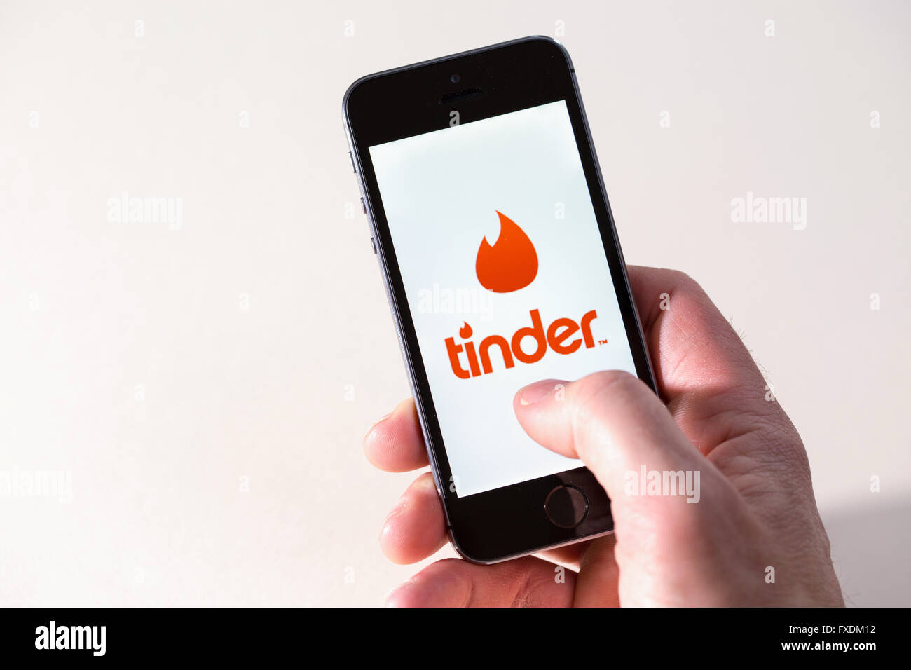 Ein Mann mit dem Zunder dating-app auf dem Handy Stockfoto
