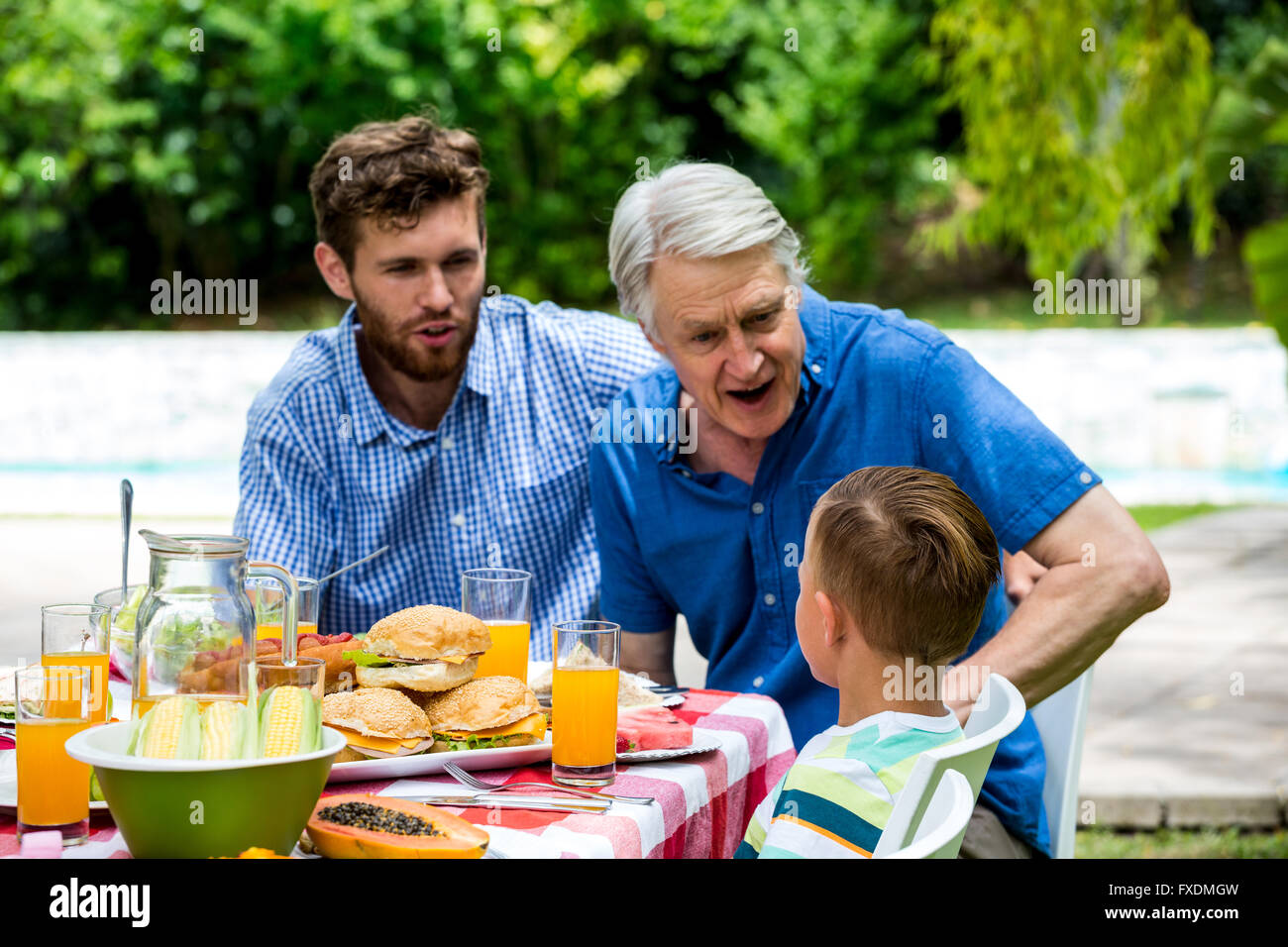 Großvater mit Sohn Gespräch mit Enkel auf dem lawn Stockfoto