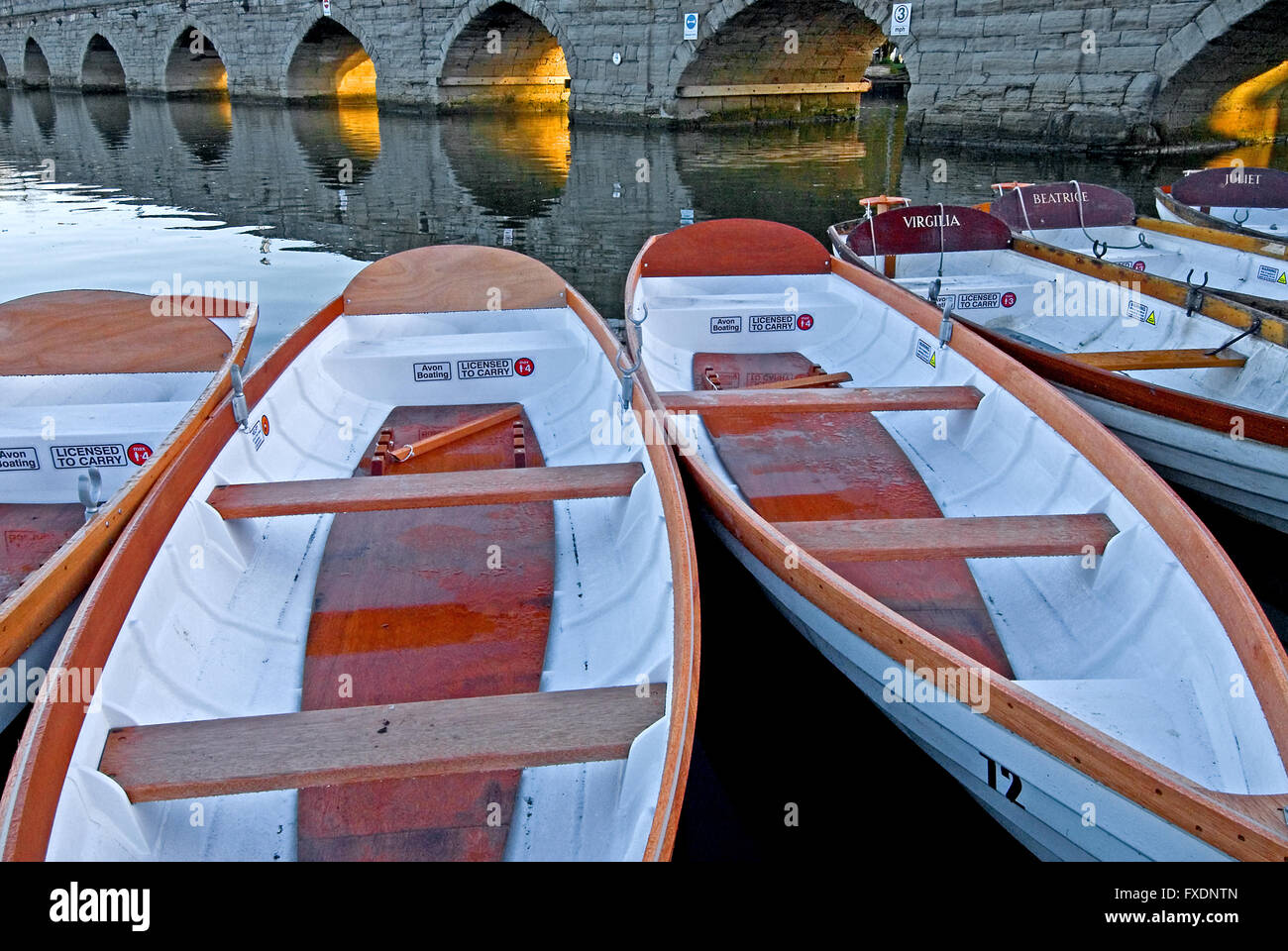 Weiße Tag Boote auf dem Fluss Avon in Stratford-upon-Avon, Warwickshire mit dem Stein gewölbt Clopton Bridge im Hintergrund. Stockfoto