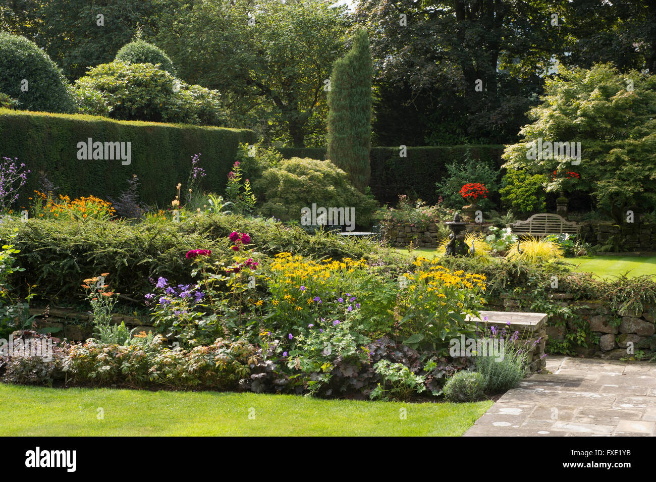 Einen privaten, traditionellen, gepflegten, ländlichen Garten, West Yorkshire, England - krautige Grenze mit blühenden Pflanzen, Weg und Rasen. Stockfoto