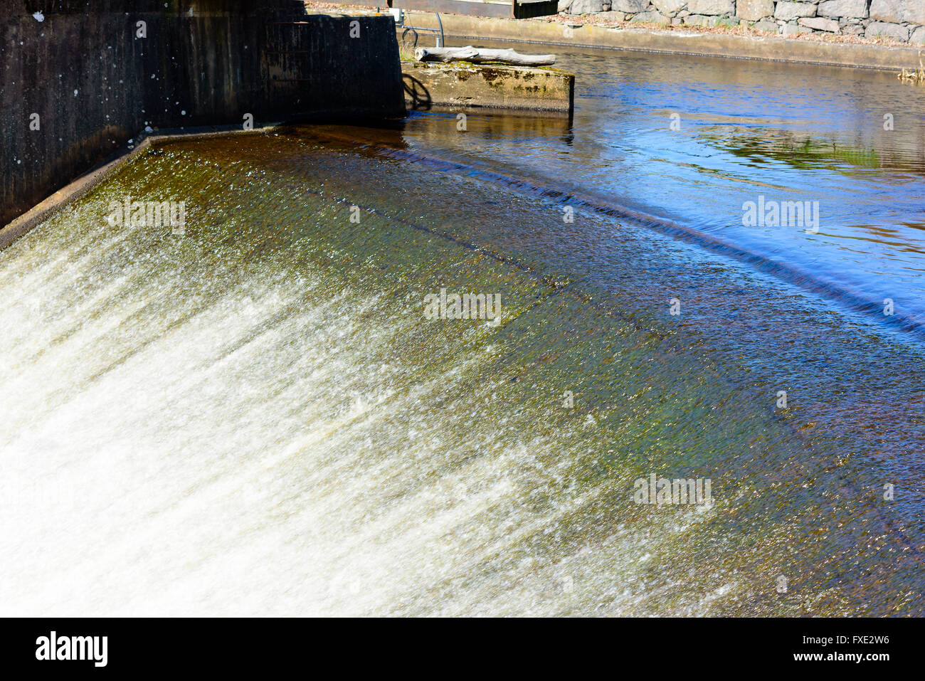 Flach und funkelnden Süßwasser Strom hinunter einen Überlauf in Lyckeby, Schweden. Das Wasser aufschäumen und Blasenbildung in der Sonne. Stockfoto