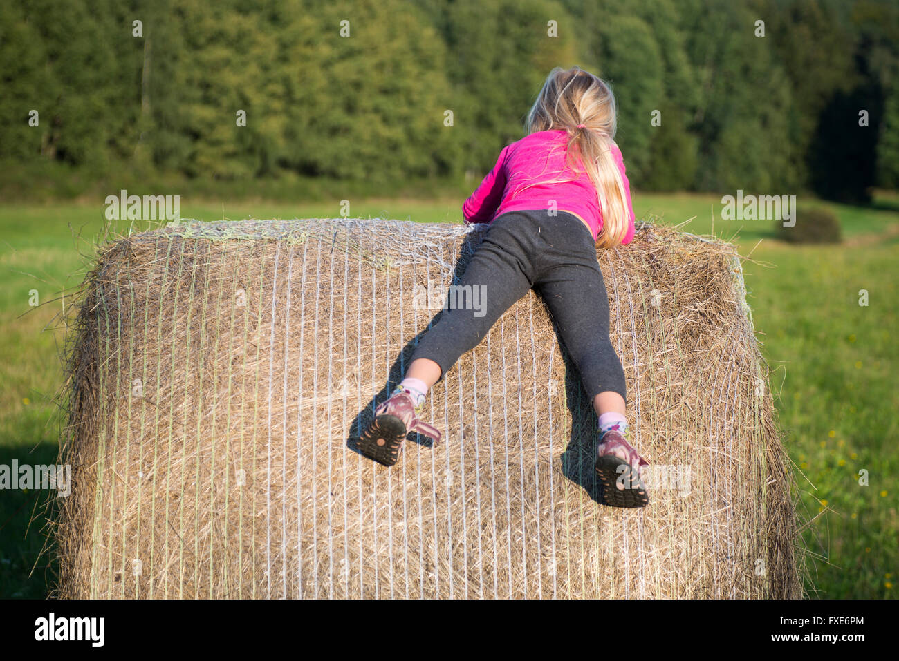 Kind blond Girl von Stroh Heuballen in Feld, Wiese, spielen, Kinder-Sommer-Aktivitäten Stockfoto