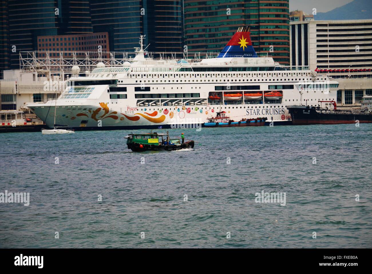 Ein kleines Boot vor einem Kreuzfahrtschiff im Hafen von Victoria Hong Kong. Stockfoto