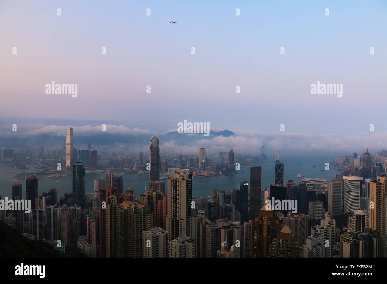 Hong Kong Skyline in einem schönen bewölkten Tag über Victoria Harbour. Flugzeug am Himmel Stockfoto