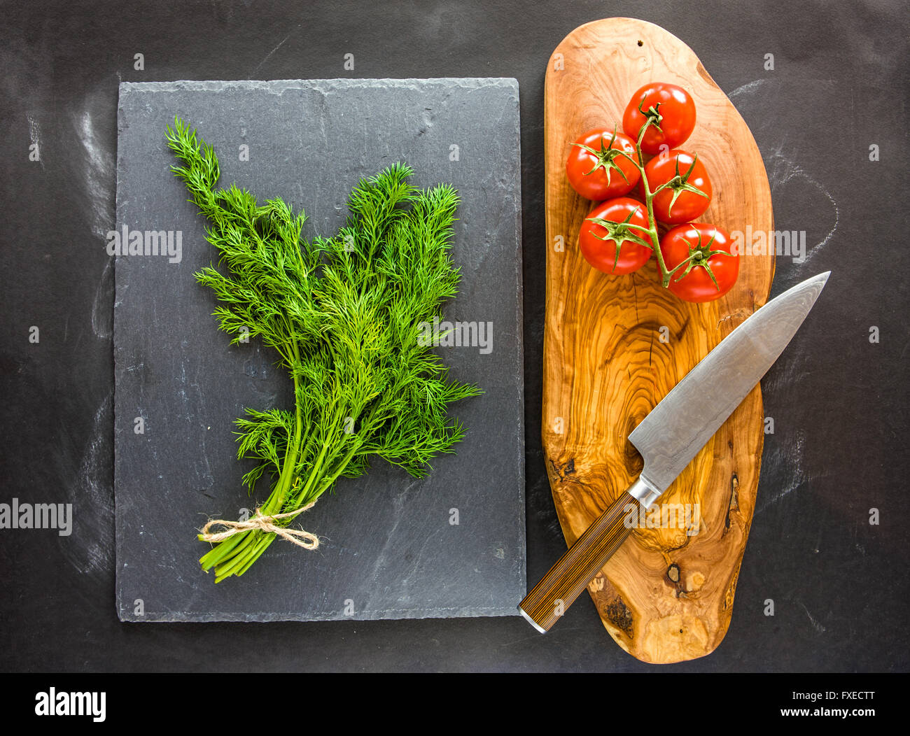 Bund Dill auf Schiefer Teller mit Tomaten auf Seite. Stockfoto