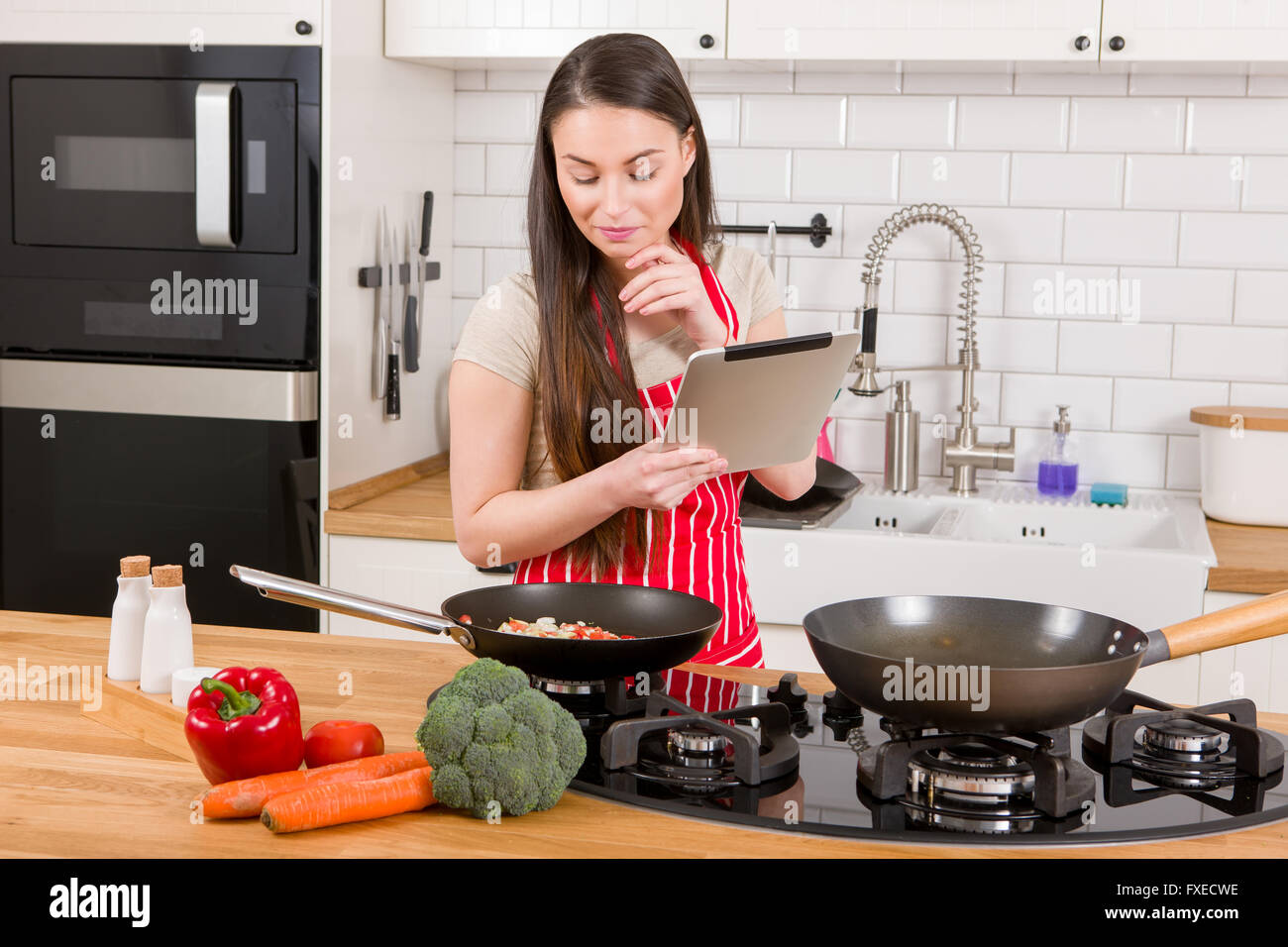 Kaukasische attraktive Frau mit Tablet-PC in der Küche. Stockfoto