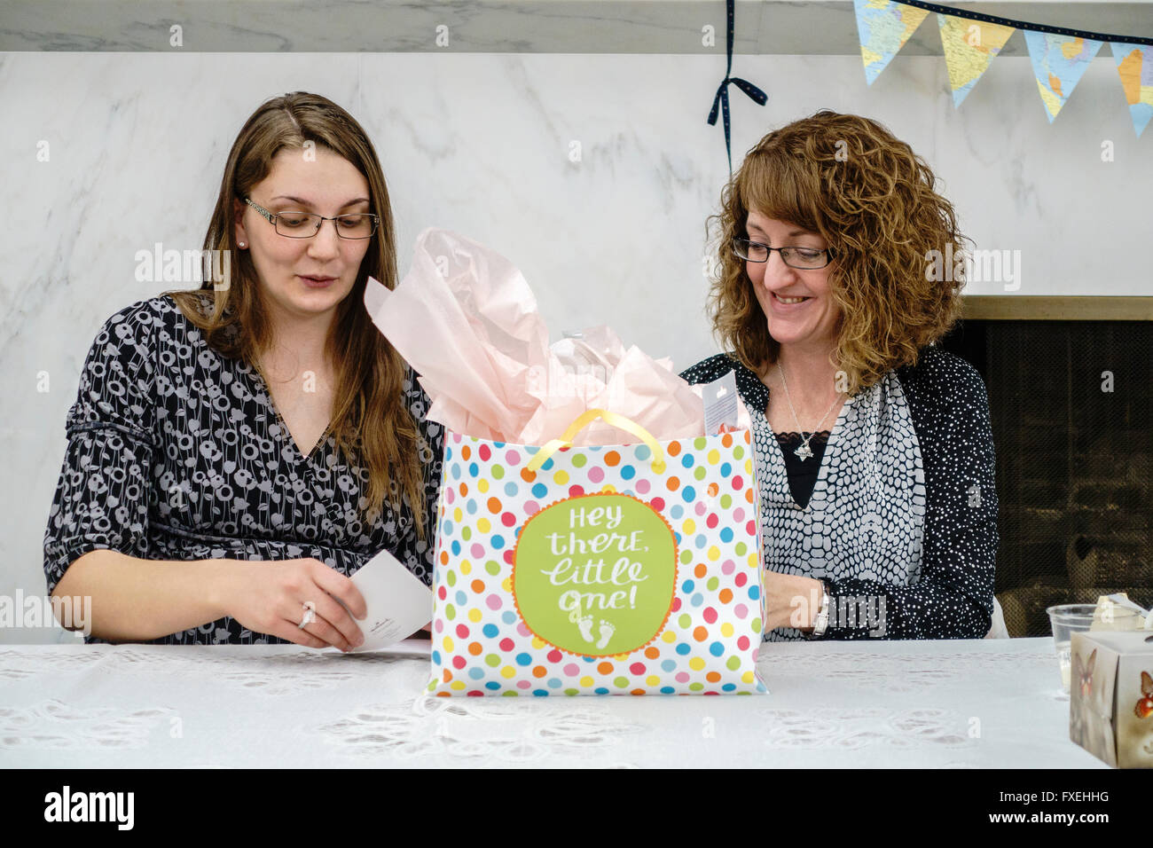 Eine werdende Mutter öffnet ihr Babyduschegeschenke während von ihrer Schwiegermutter unterstützt. USA. Stockfoto