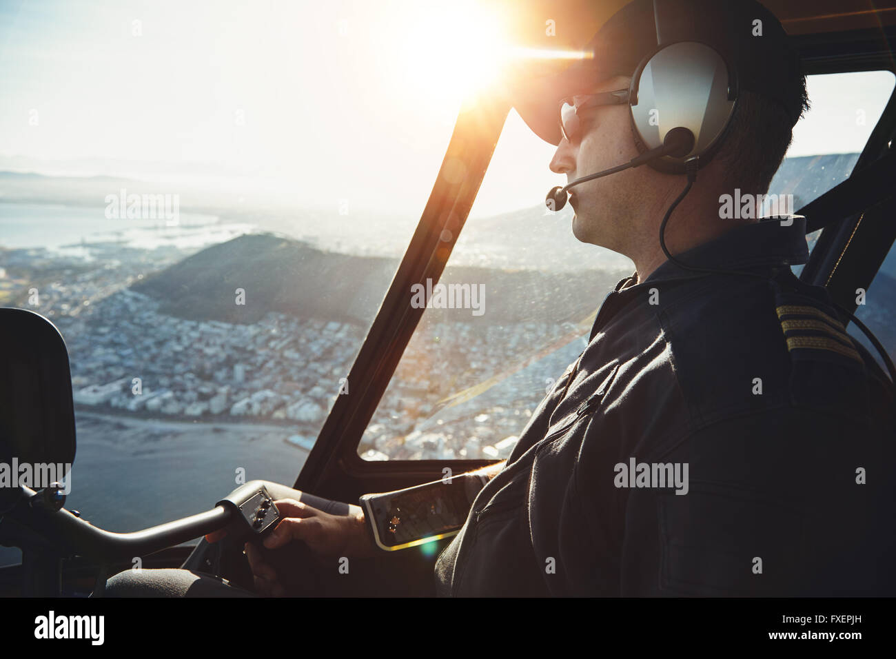 Nahaufnahme eines männlichen Hubschrauberpiloten fliegen über die Stadt Kapstadt an einem sonnigen Tag. Stockfoto