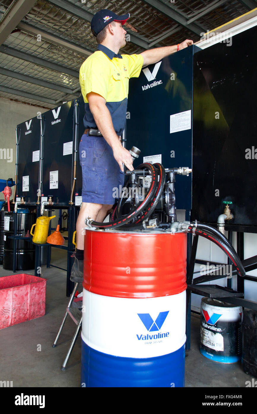 Mann 40 Gallone Trommel einfüllen von Motoröl, North Coast Petroleum, New South Wales Australien Stockfoto