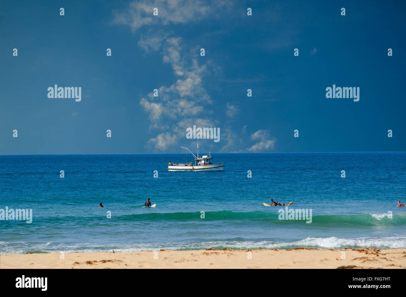 Boot fangen Fische und Surfer Wellen Stockfoto