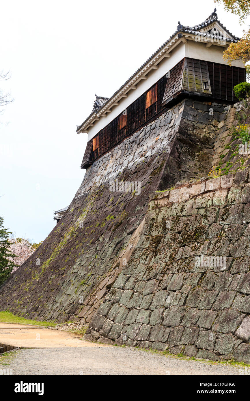 Japan, Schloss Kumamoto. Gennoshin L-förmige Yagura, Revolver, Eckstein Loch fallen. Gebogene hohe ishigaki Trockenmauern. Bewölkten Himmel. Stockfoto