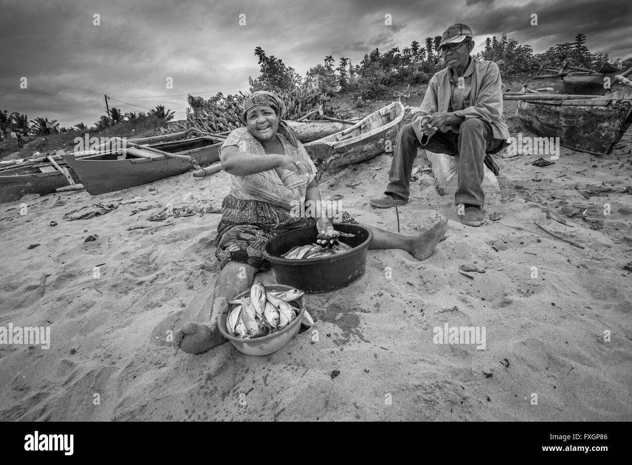 Mosambik, eine Frau ist das Kochen Fisch mit Fischer am Strand, schwarz und weiß, B&W. Stockfoto