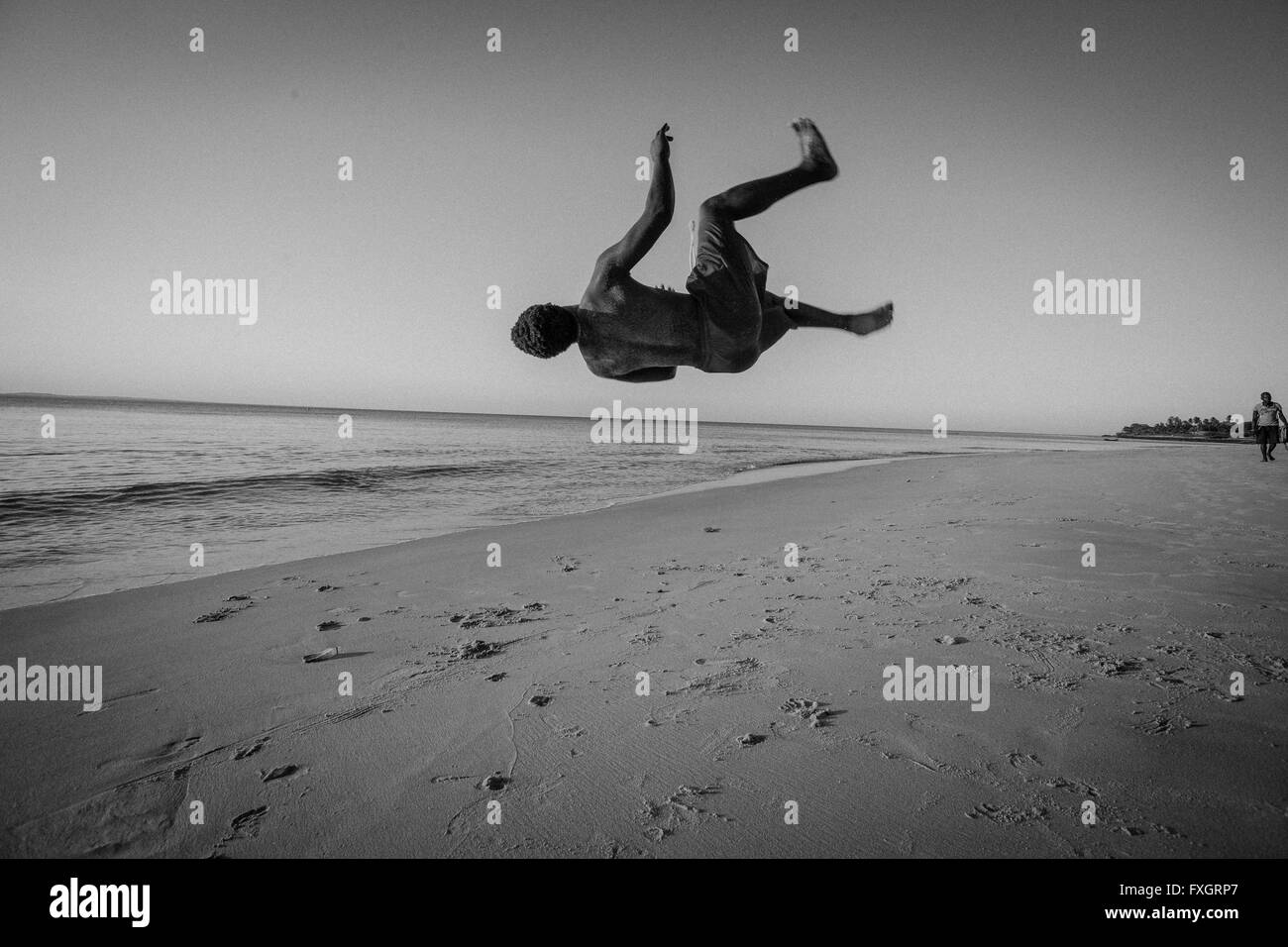 Mosambik, Afrika, ein Mann springt in die Luft durch Glück am Strand bei Sonnenuntergang, schwarz und weiß. Stockfoto