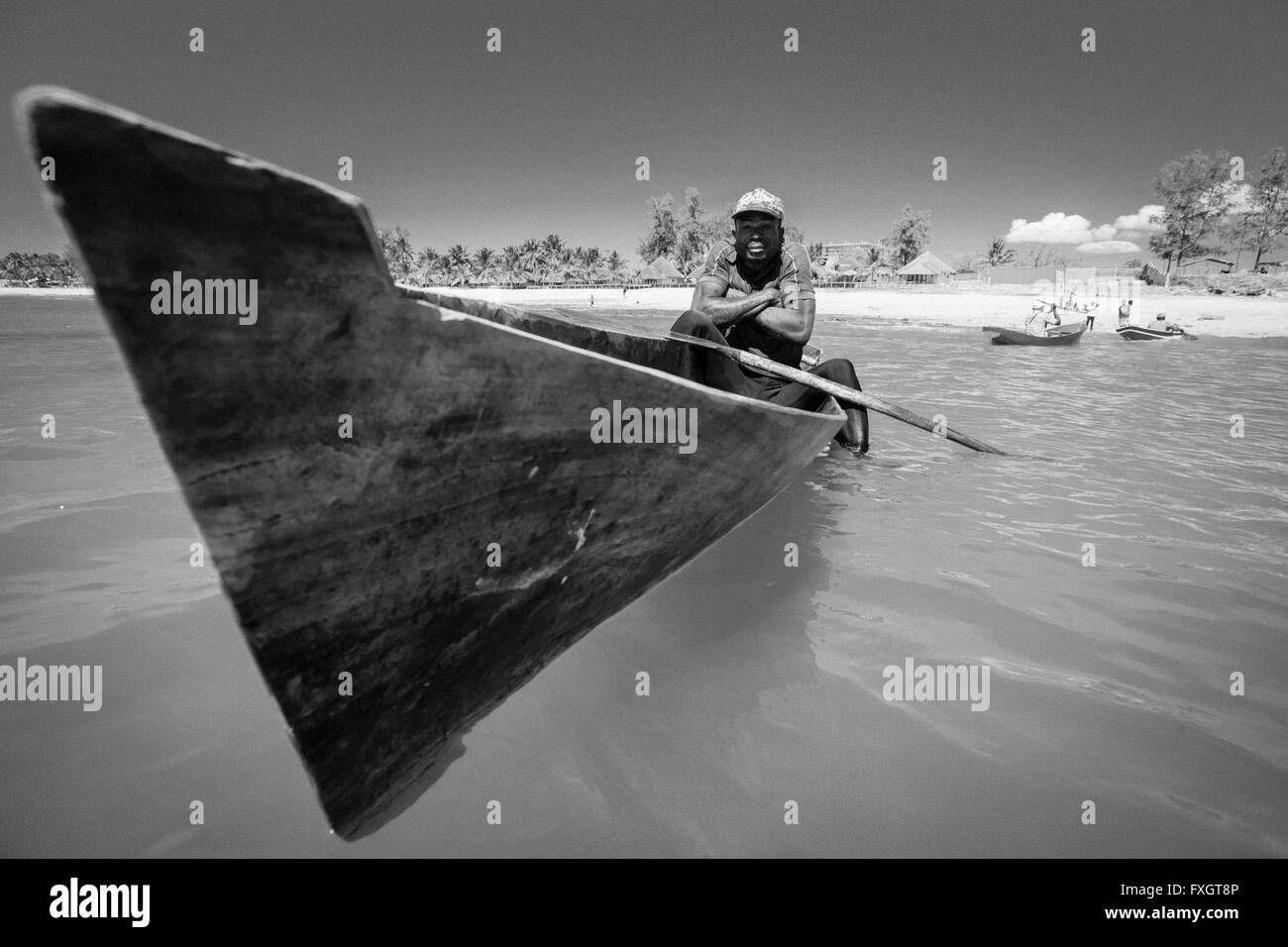 Mosambik, Afrika, ein Fischer im Boot im Meer, weißer Strand, schwarz und weiß. Stockfoto