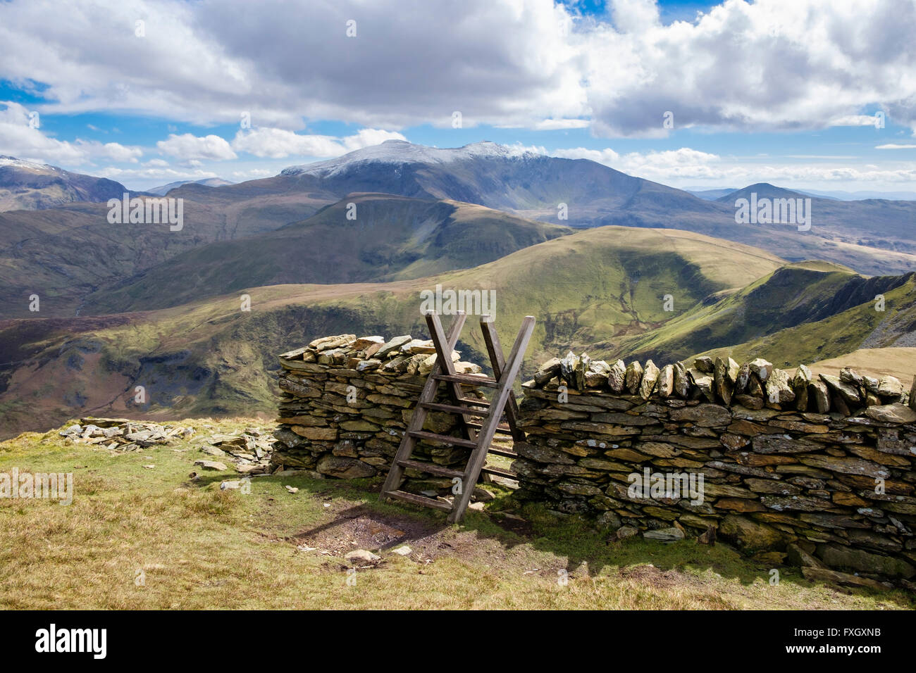 Blick auf schneebedeckte Mount Snowdon mit Stil über trockenmauern Wand an Vordergrund Pfad auf der Moel Eilio in Snowdonia National Park (Eryri), Wales, Großbritannien Stockfoto