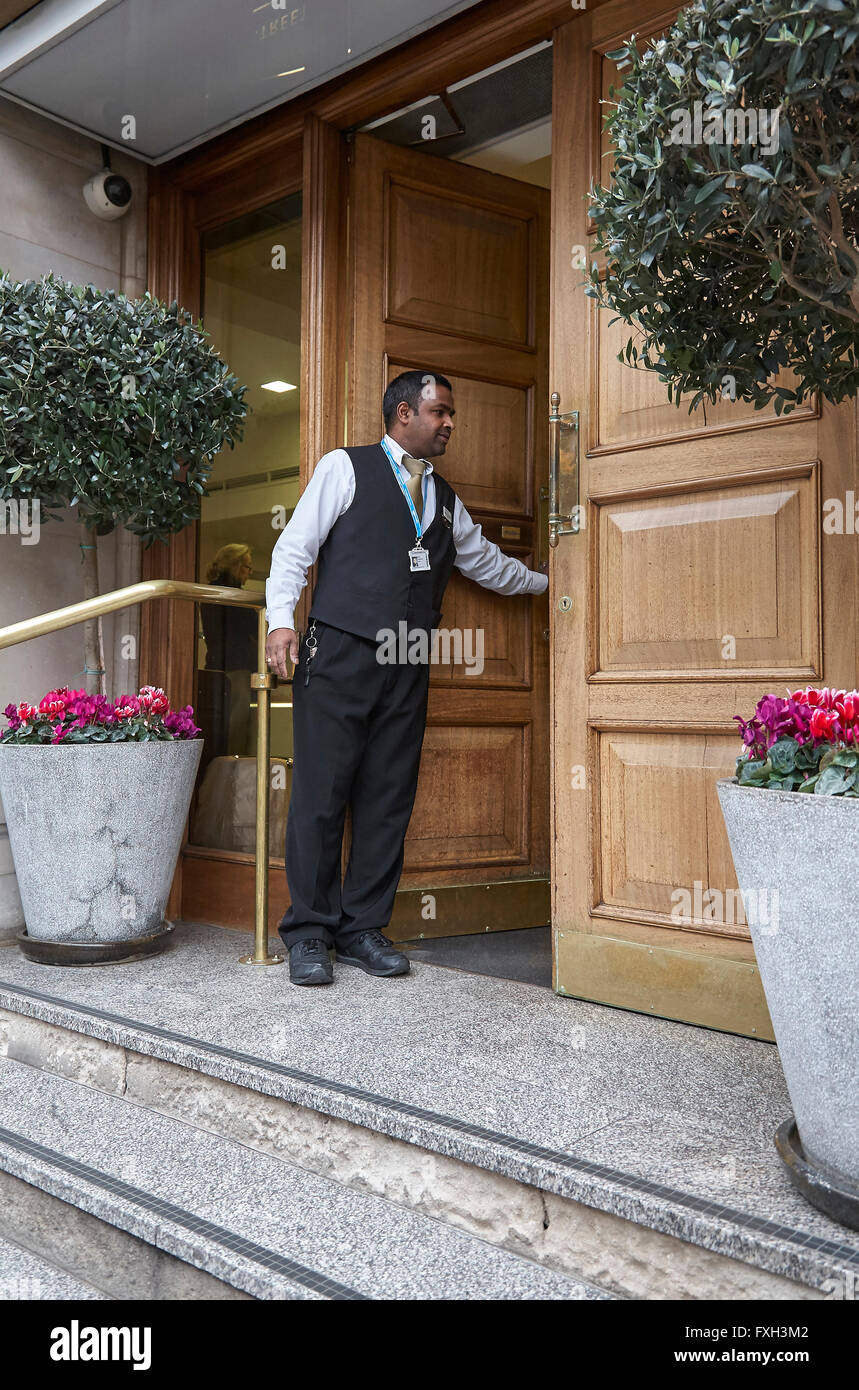 Ein Hotelpagen oder Porter Öffnen der Haustür eines Hotels für einen Gast im Vereinigten Königreich. Stockfoto