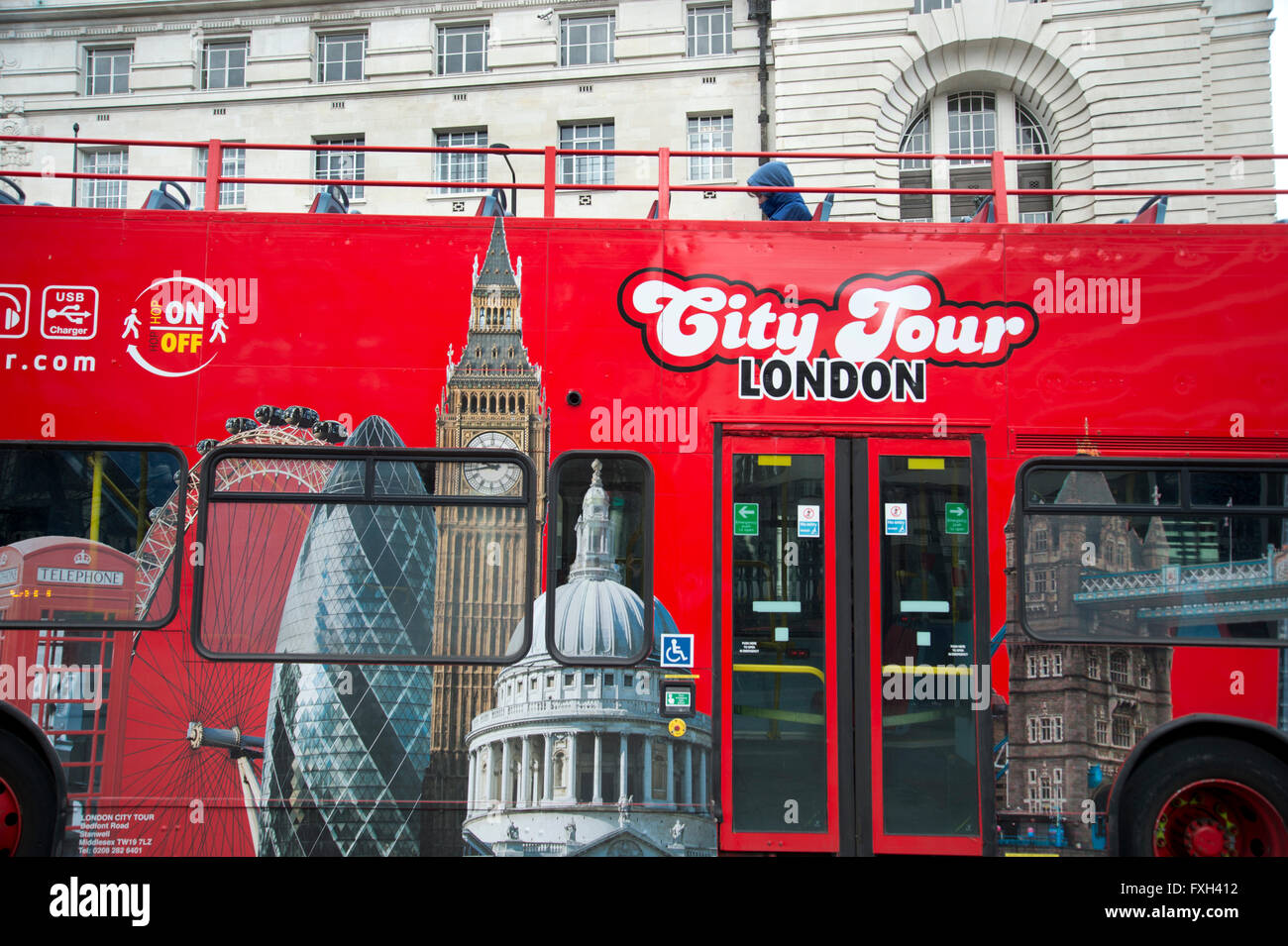London. Eine einsame Figur an Bord eine Stadtrundfahrt Touristenbus auf Westminster Bridge. Der Bus ist mit Sehenswürdigkeiten verziert. Stockfoto