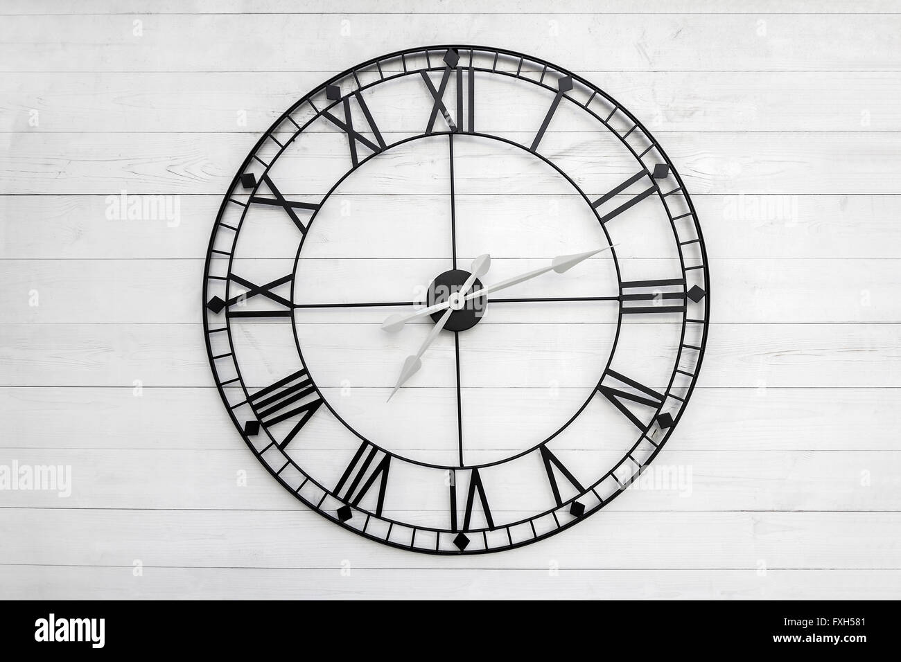 Schwarze Wanduhr auf weißem Holz Hintergrund Stockfoto