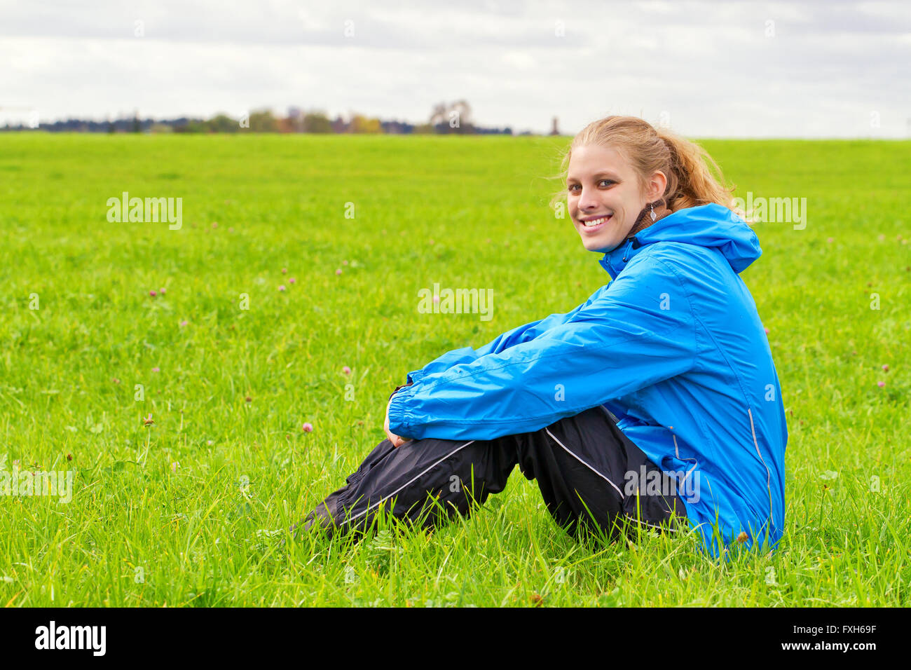 Glücklich, sportliche Frau sitzt auf einer grünen Wiese Stockfoto