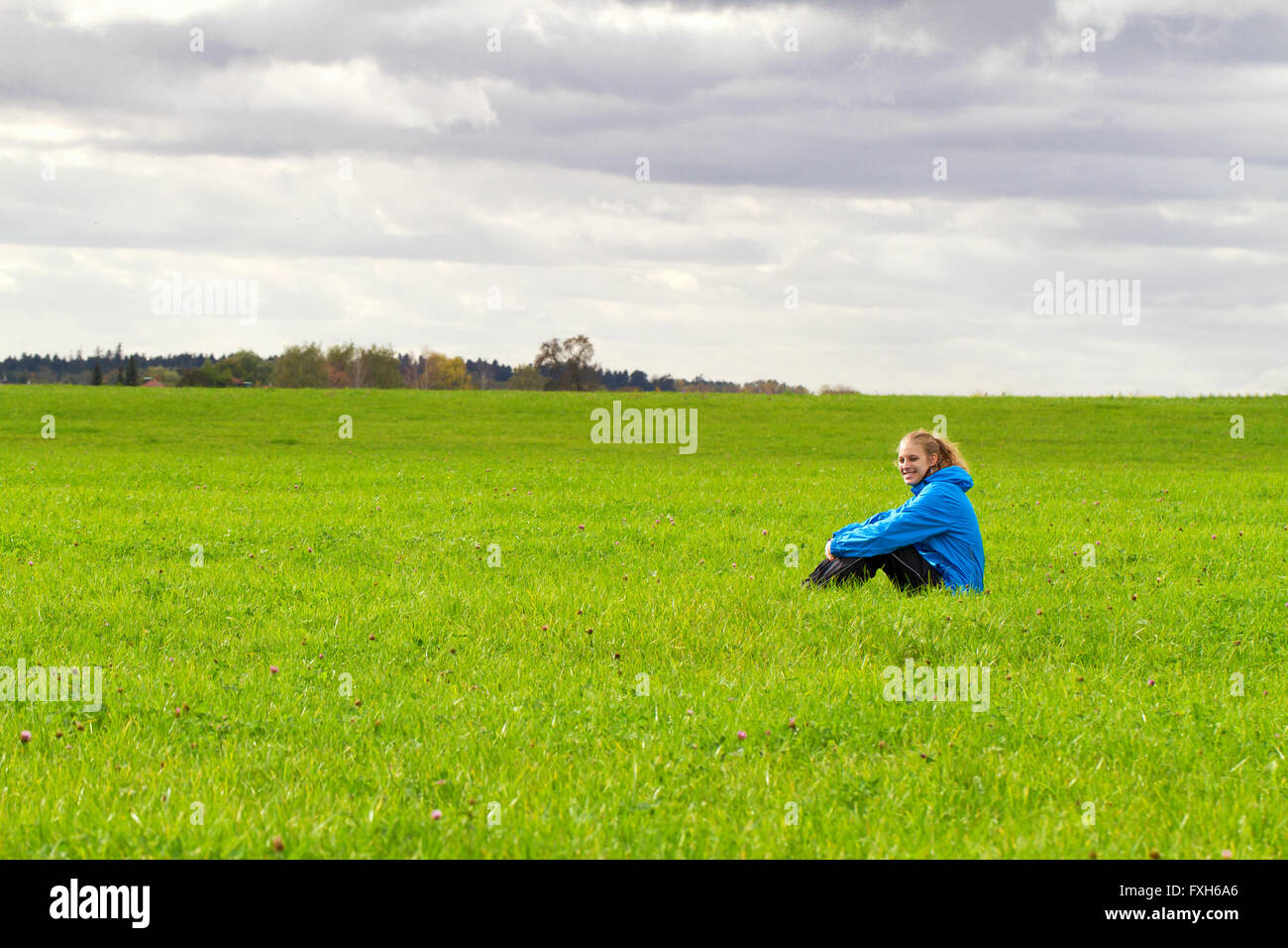 Glücklich, sportliche Frau sitzt auf einer grünen Wiese Stockfoto