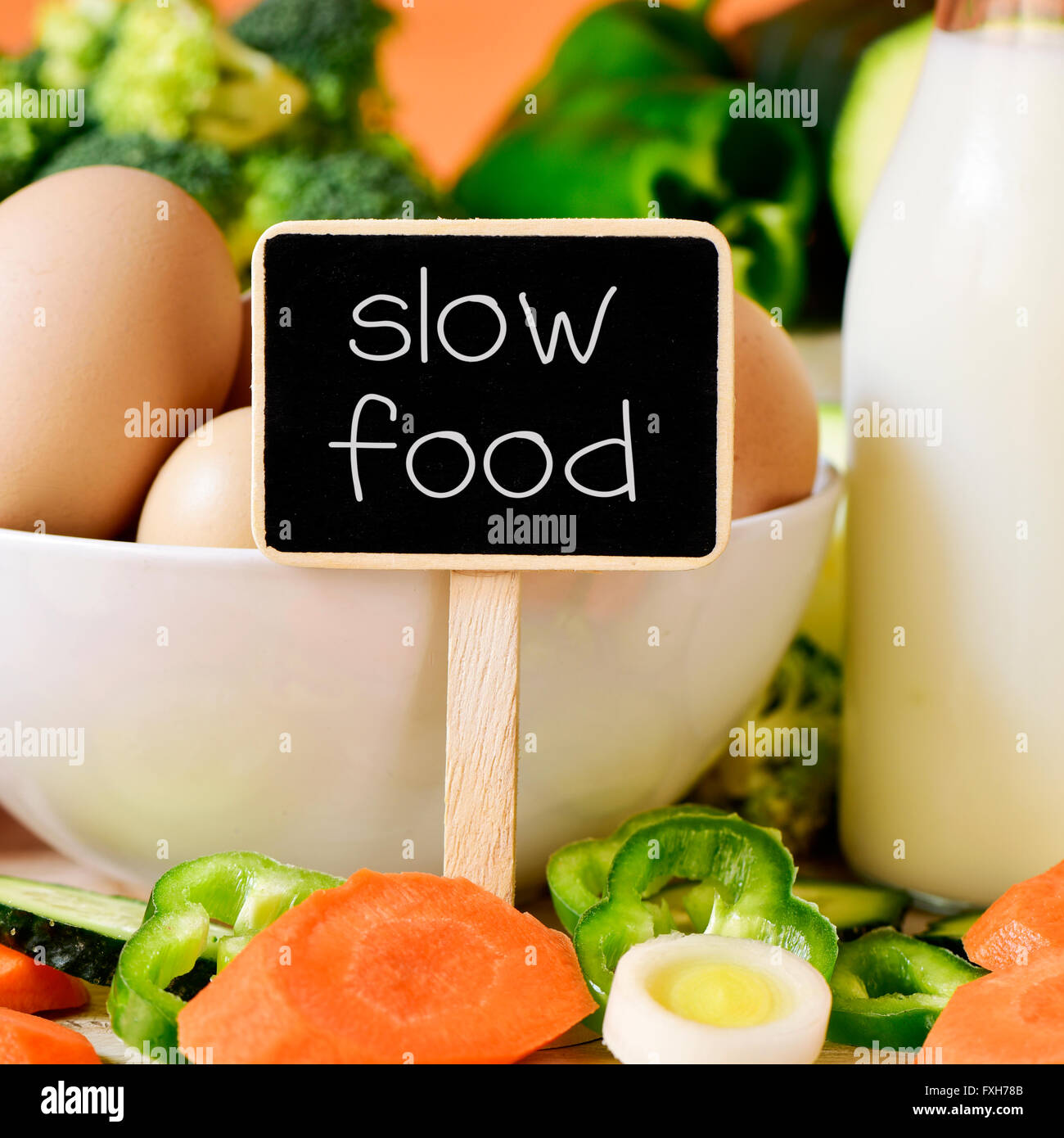 Nahaufnahme von einem Schild mit dem Text slow-Food auf ein Tisch voller verschiedener Rohkost, ein Schüssel mit einigen Hühnereiern und ein Stockfoto