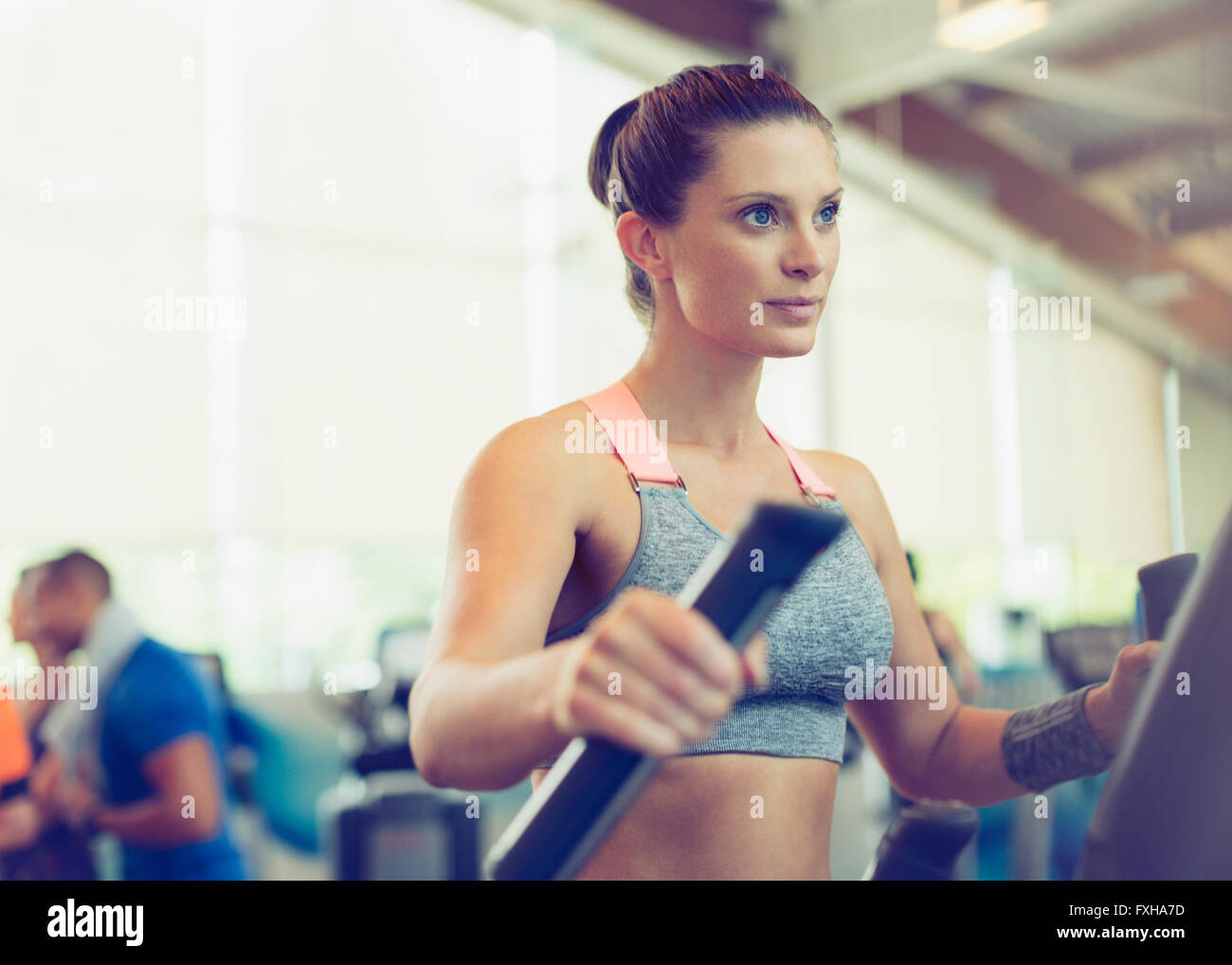 Fokussierte Frau Training auf Crosstrainer im Fitness-Studio Stockfoto