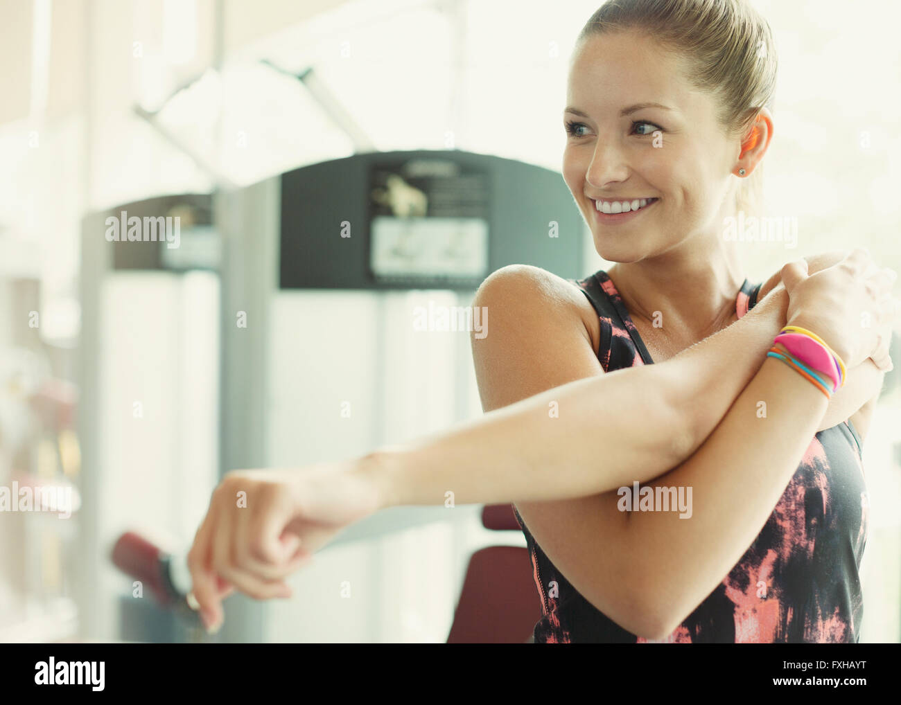 Lächelnde Frau stretching Arm am gym Stockfoto