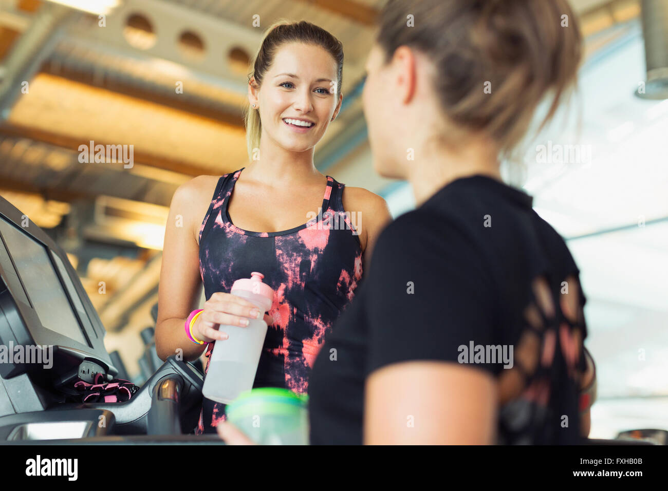 Lächelnde Frauen reden und Trinkwasser in Turnhalle Stockfoto