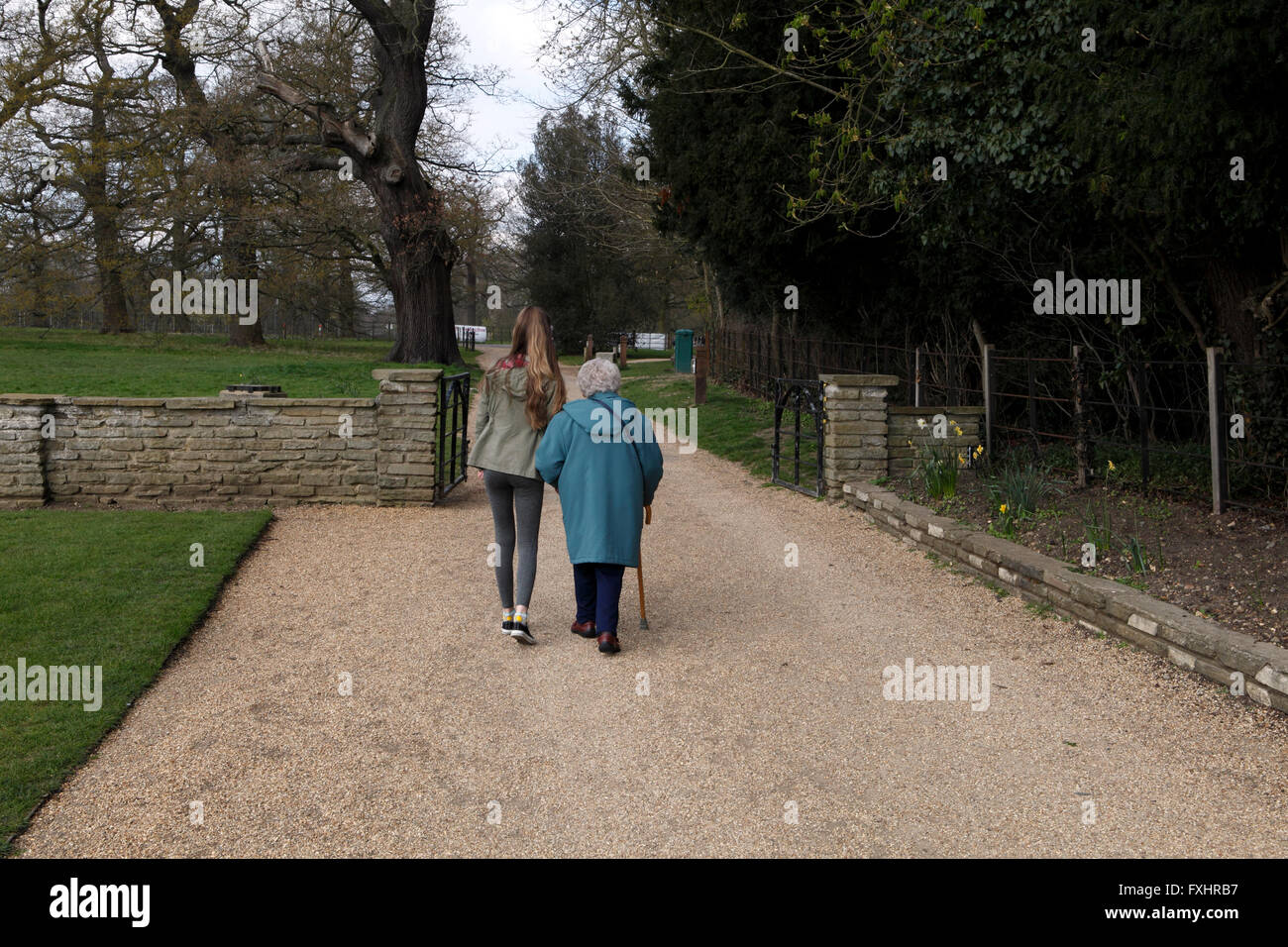 Eine Großmutter und Enkelin in einem Park spazieren. Achtzigjährigen mit einem Teenager Pflegeperson Hepler. Stockfoto