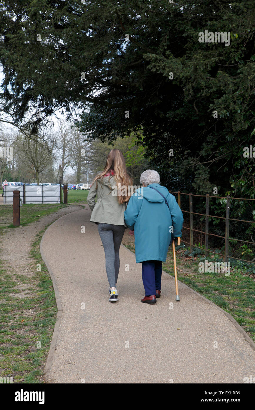 Eine Großmutter und Enkelin in einem Park spazieren. Achtzigjährigen mit einem Teenager Pflegeperson Hepler. Stockfoto