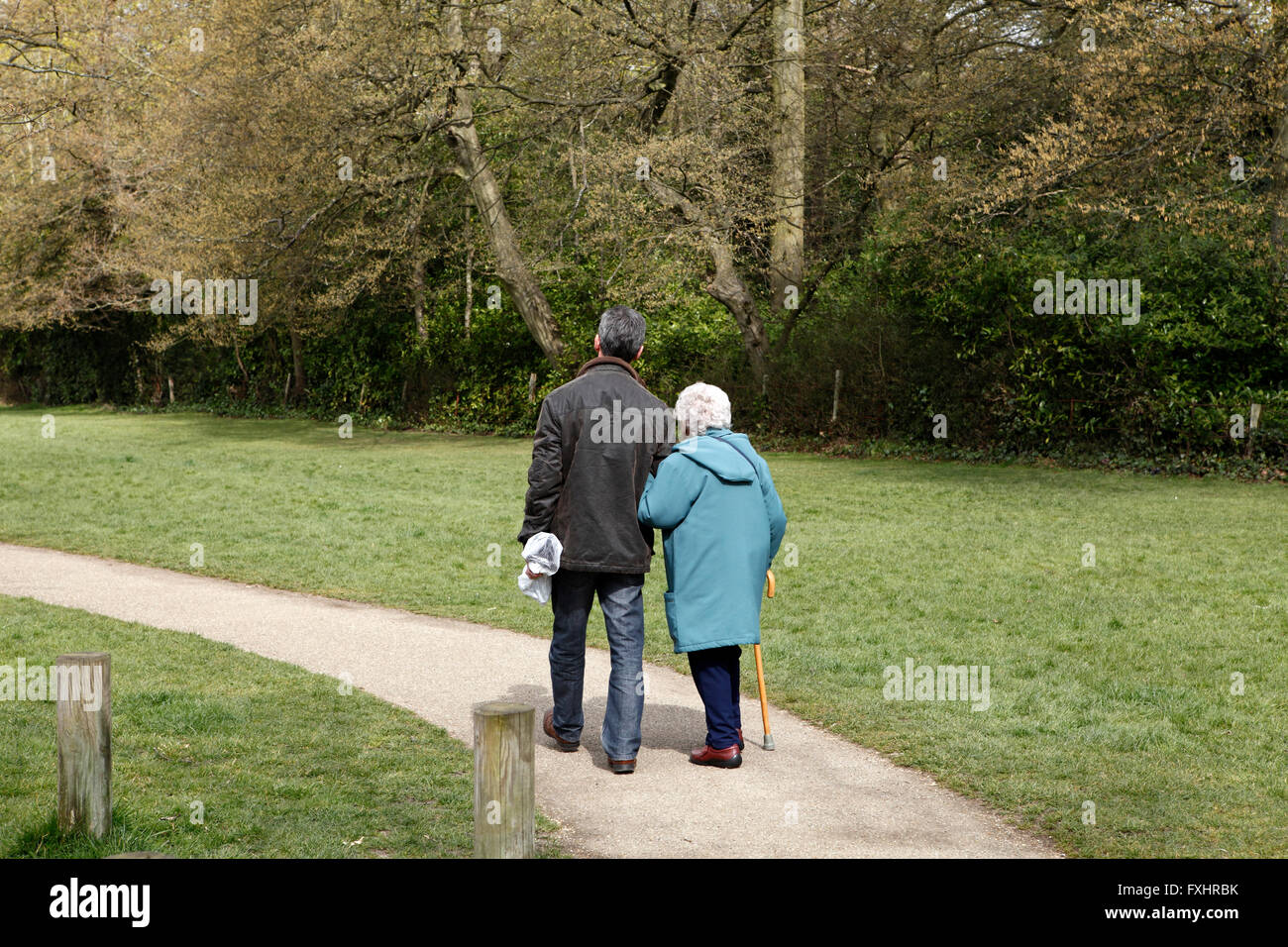 Mann beim Spaziergang mit seiner Mutter im Ruhestand. Hinten Sie Ansicht von. Stockfoto