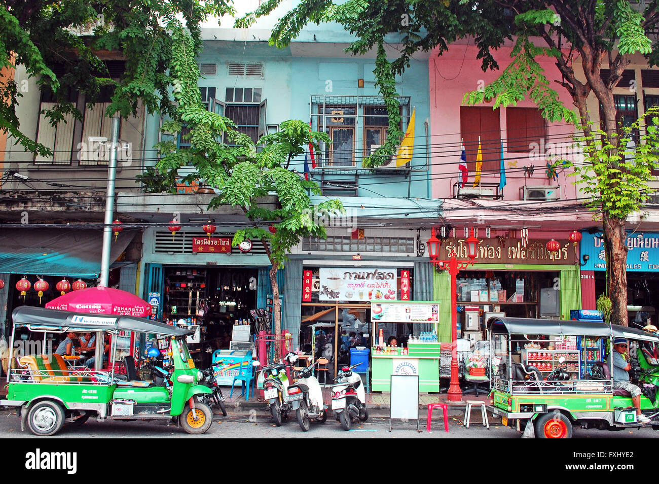 Thai Street in Chinatown, mit kleinen Geschäften, Tuk-Tuks, Roller und Motorräder, die Gebäude farbigen blau und rosa Stockfoto