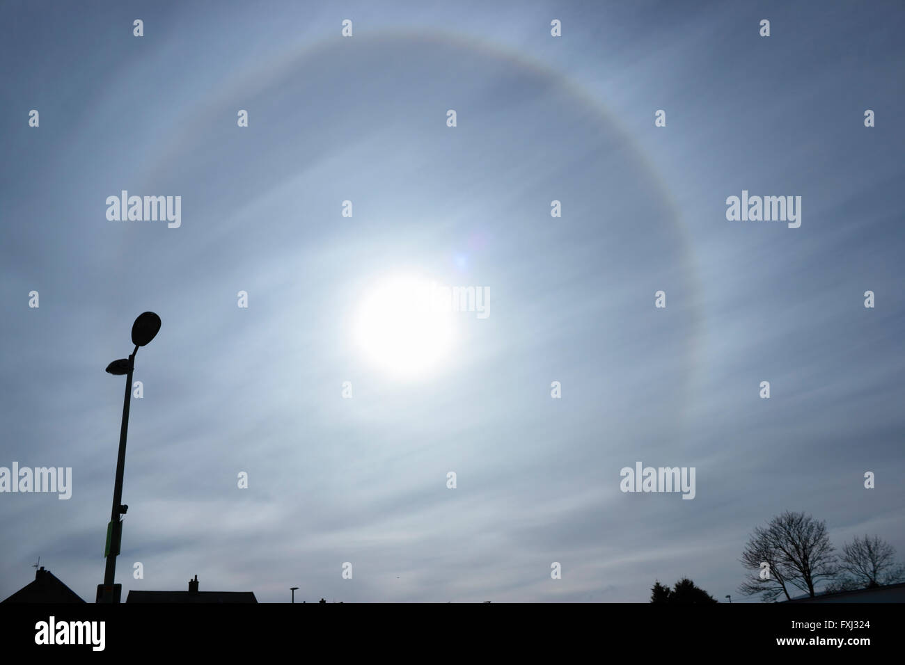 Eine ungewöhnliche 22° Halo kreisförmigen Regenbogen um die Sonne durch die Beugung von Licht durch Eiskristalle in der Atmosphäre verursacht. Sun Hund. Stockfoto