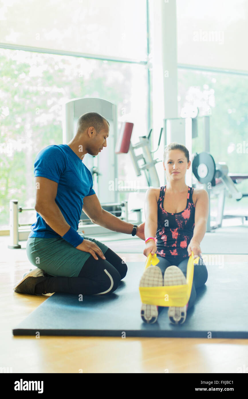 Persönlicher Trainer leiten Frau stretching Beine mit Widerstand Band am gym Stockfoto