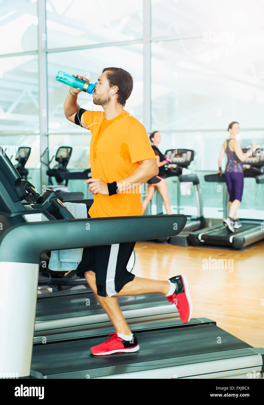 Mann, Trinkwasser und laufen auf dem Laufband im Fitnessstudio Stockfoto