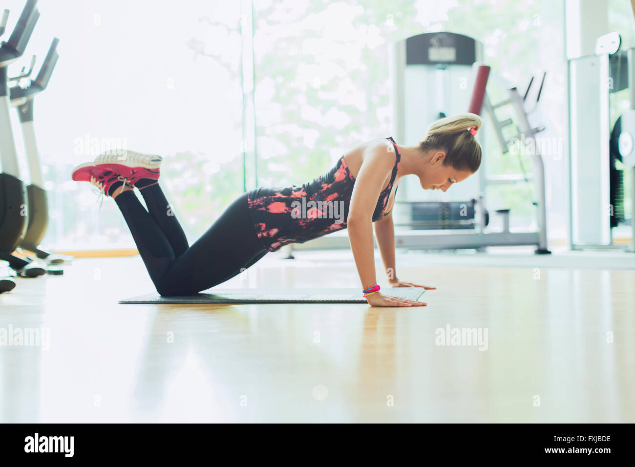 Frau macht Liegestütze auf Knien beim Fitness-Studio Stockfoto