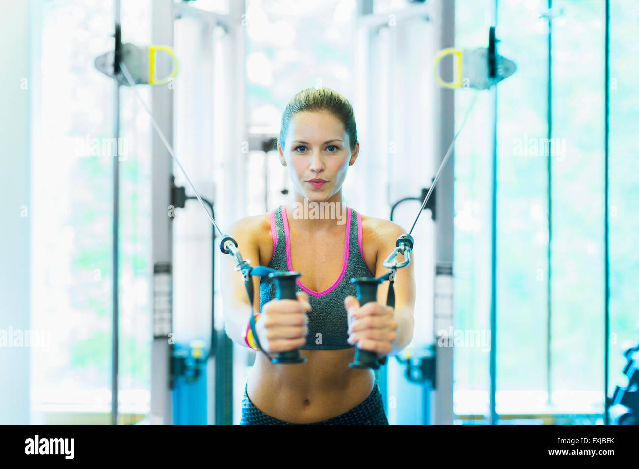 Fokussierte Frau mit Kabel Trainingsgeräten im Fitnessstudio Stockfoto