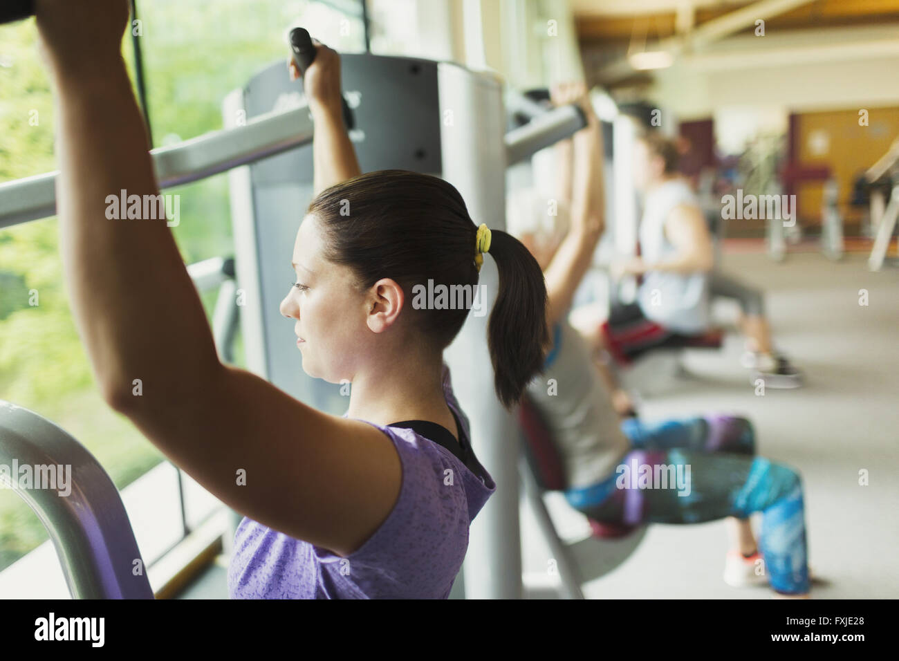 Konzentrierte sich Frau mit Trainingsgeräten im Fitnessstudio Stockfoto