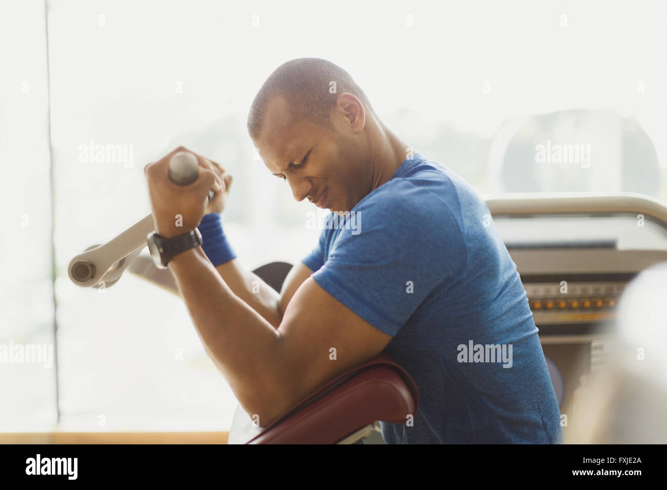 Mann tut Bizeps curls ein Trainingsgeräten im Fitnessstudio Stockfoto
